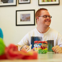 A man with Down Syndrome weaves a colourful basket