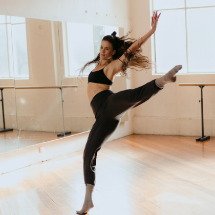 A young dancer leaping in a bright dance studio.