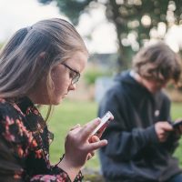 Two people sitting looking down at their smartphones.