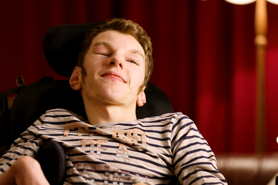 Young man wearing a striped tee shirt, smiling to camera.