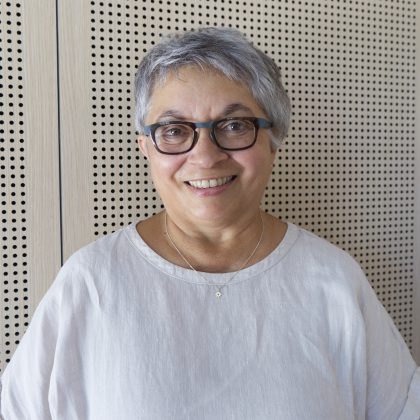 Jackie Weinman, wearing glasses, smiles at the camera. She is wearing a white shirt.