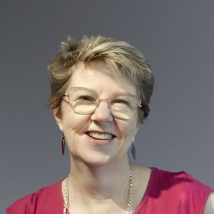 Dr. Michelle Bunn is wearing a sapphire pink sleeveless top. She smiles at the camera.