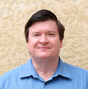 Portrait of Scott La Vertu. He is wearing a blue collared shirt with a subtle pattern.