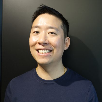 Stanley Lai smiles widely at the camera. He is wearing a dark blue polo shirt.