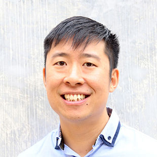 Stanley Lai smiling at the camera. He wears a light blue shirt with a two layered collar.