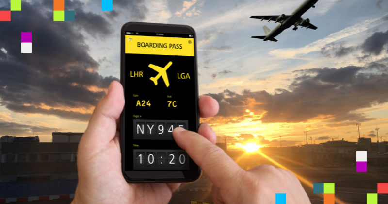 Image is of a hand holding a smart phone with a boarding pass on the screen. The background is a runway scene at an airport. A plane is flying through a sunset strewn sky. 