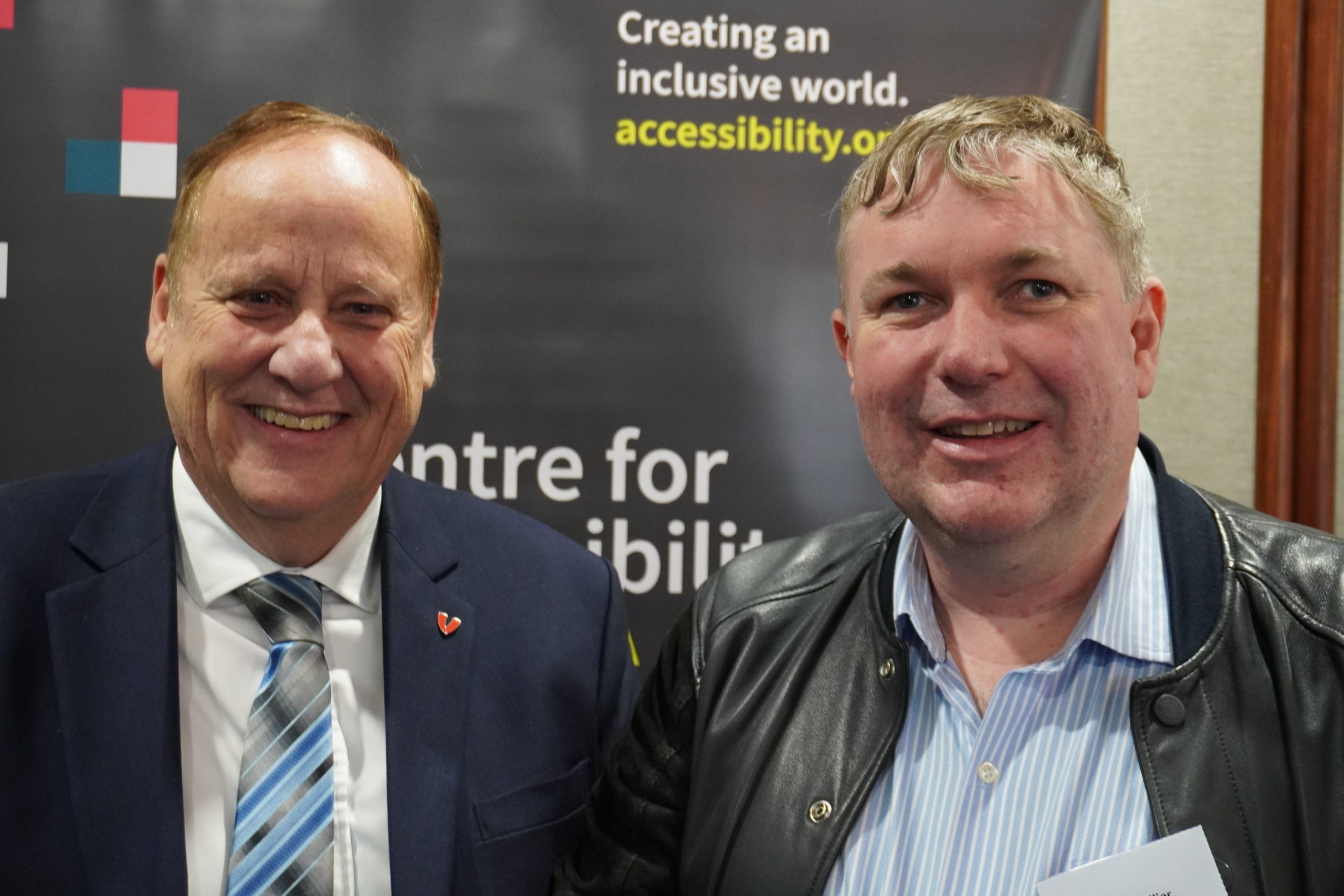 Image is of the Honourable Don Punch and Dr. Scott Hollier smiling, in front of the CFA Australia banner.