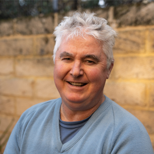 Chris Leighton, smiling, and wearing a light blue jumper.