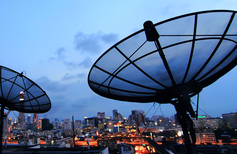 Satellite dishes with a background of city lights.