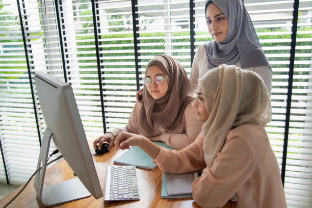 A group of women seated around a laptop.