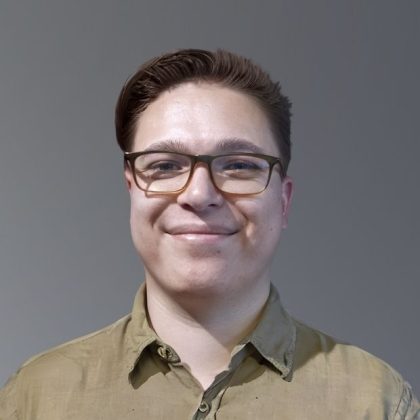 Ryan is smiling at the camera. He is wearing glasses and a collared shirt.