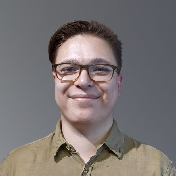 Ryan is smiling at the camera. He is wearing glasses and a collared shirt.